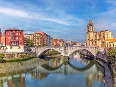 A bilbaói San Antón-híd és a San Antón-templom a Nervión-folyó felett, színes épületekkel a háttérben.