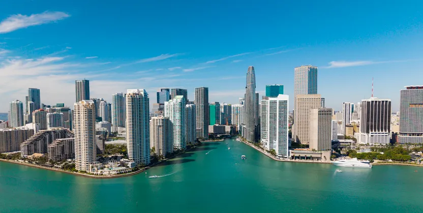 Miami modern belvárosának felhőkarcolói a türkizkék folyó és a tenger találkozásánál, madártávlatból.