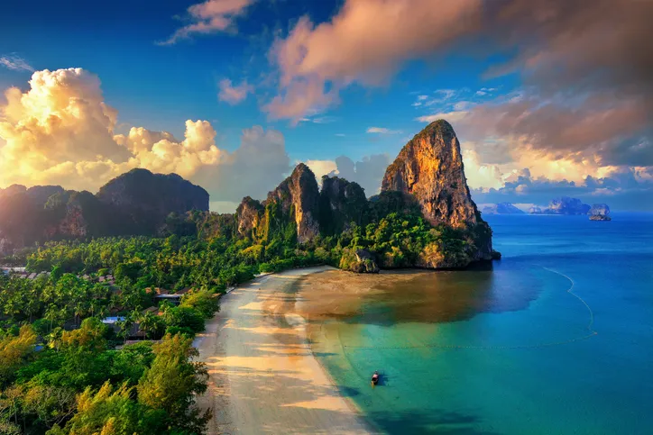 A krabi Railay Beach madártávlatból, hatalmas mészkősziklákkal, sűrű trópusi erdővel és türkizkék tengerrel naplementében.
