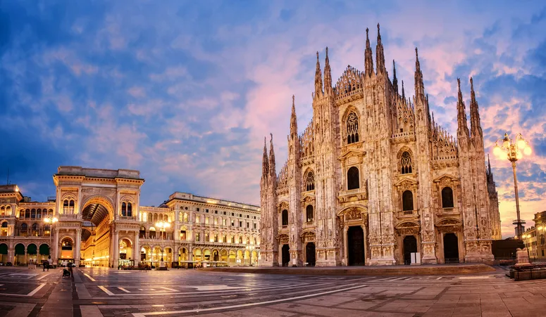 A milánói dóm gótikus épülete és a Galleria Vittorio Emanuele II bejárata naplementekor a dóm téren, Olaszország.