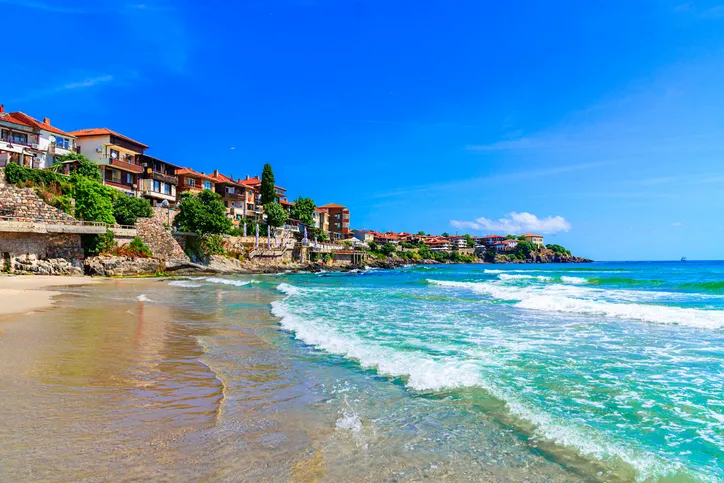 Szozopol óvárosának tengerparti házai és a homokos strand a tiszta, kék vizű Fekete-tenger partján, Bulgária.
